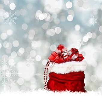 A red Christmas gift bag overloaded with tiny presents wrapped up in red, black and white wrapping paper and ribbons, against a sparkly, light backdrop.
