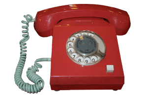 Old-fashioned red telephone with dial and cord.