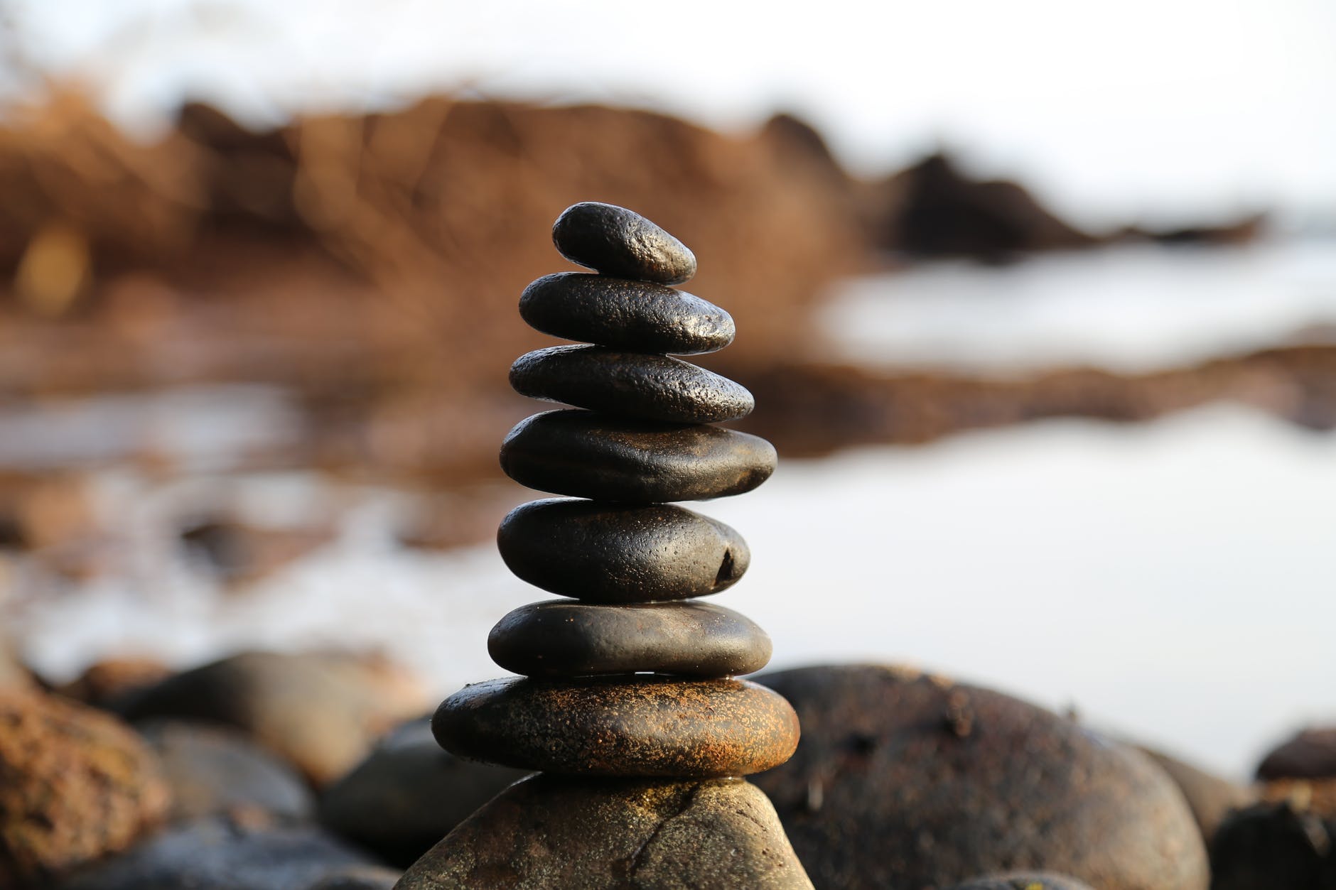 A stack of pebbles against the backdrop of the some cliffs and the sea.